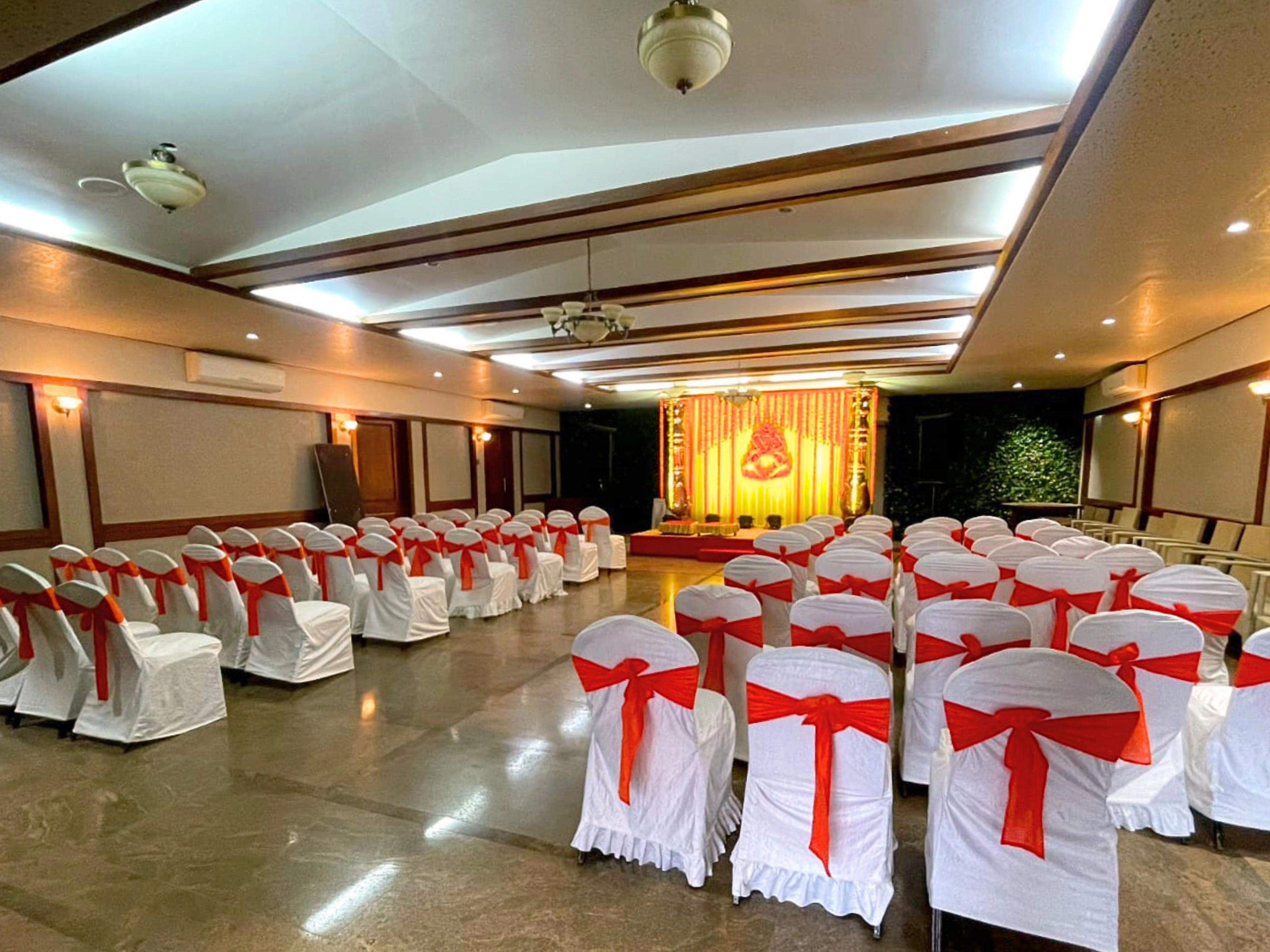 Elegant indoor conference hall with round tables and chandeliers at Ramsukh Resort, Mahabaleshwar.